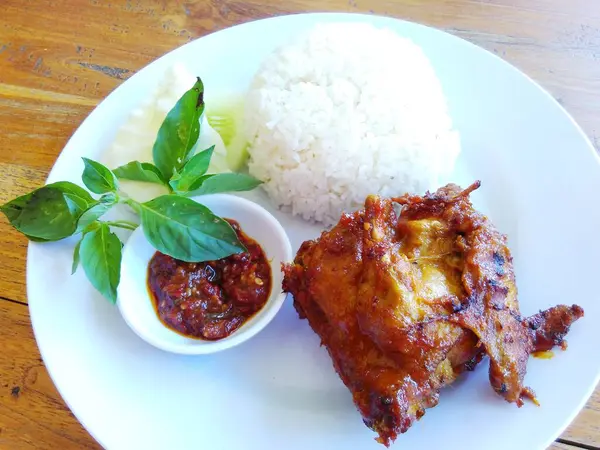 stock image A plate of rice with grilled chicken, fresh vegetables and sambal, Indonesian food