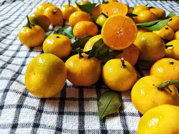 Fresh orange fruits with leaves as background, top view