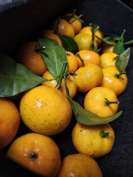 Fresh orange fruits with leaves as background, top view