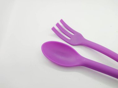 Büyük mor plastik kaşık ve çatal, beyaz arka planda izole edilmiş.