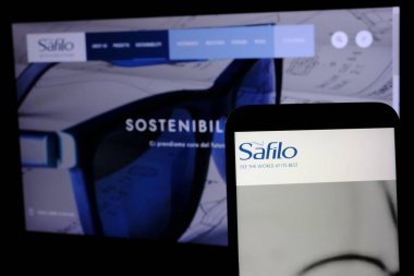 Önplanda Safilo Grubu 'nun kaplıca logosu cep telefonundan ve arka planda şirketin web sitesinin Euronext Milan segmentinde yer alan Milan Borsası' nda listelenen bir sayfası görülüyor..