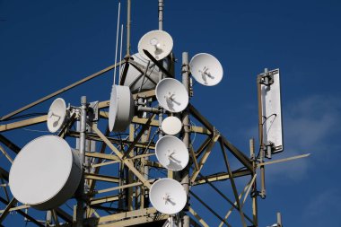 Telekomünikasyon direğine bağlanmış internet sinyalini yayınlamak için bir grup mini uydu antenleri..