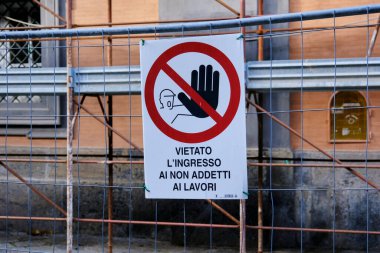 Bu girişin profesyonel olmayanlara yasak olduğunu belirten bir inşaat alanı tabelası. İşaret, inşaat alanının sınırlarını aşan metal bir bariyere yapıştırılmış..