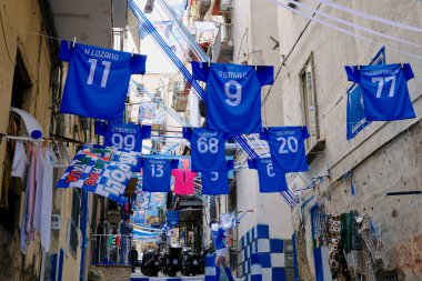 The eleven Napoli Calcio shirts that contributed to the victory of Napoli Calcio's third Scudetto. Among the shirts that of Osihmen. In the background a silhouette of Diego Armando Maradona. clipart