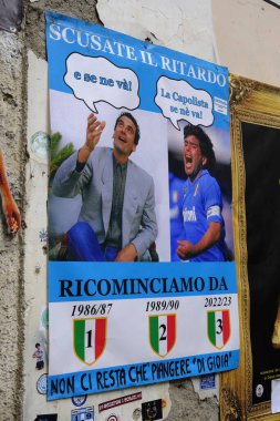 Poster, Massimo Troisi 'ye devam eder ve şöyle der:' ve uzaklara gider 'Diego Maradona' nın sevinçli görüntüsü şöyle cevap verir: 'The Capolista gider'. Napoli, 2022 / 23 sezonunda ligde ilk sırada yer alıyor. Largo Maradona, Napoli.