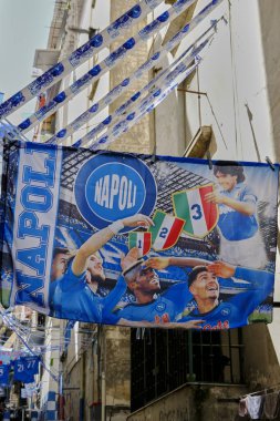 SSC Napoli bayrağı bugünün oyuncularıyla ve Diego Armando Maradona ile, futbol takımının kazandığı üç şampiyonlukla.
