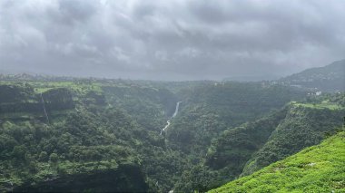 Bir dağ vadisine kurulmuş şelale, tepede beliren gri bulutlar, nefes kesici ve huzurlu bir manzara yaratıyor..