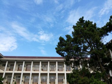 Yogyakarta, Indonesia. February 14, 2016. Beautiful and green gadjah mada university building with clear blue sky and clouds background