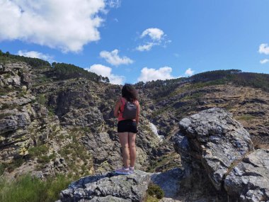 Portekiz 'in Fisgas de Ermelo kentinde bir şelalenin indiği arka plandaki dağa bakan turist kadın.