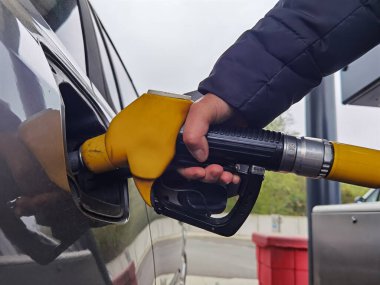 Benzin istasyonunda yakıt pompası ve yakıt ikmali yapan bir araba.