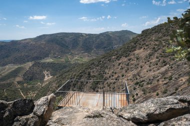 Bazı kayaların ve arka plandaki dağların arasında, Portekiz 'in Pinhal do Douro kentindeki Fraga da Ola' nın metalik yapısı