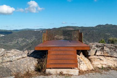 Dağlar ve bazı kayalar arasında, Portekiz 'in Castanheiro do Norte şehrinde Olhos do Tua' ya bakılır. Bazı kayaların üzerinde kırmızımsı pas tonları olan metal yapı.