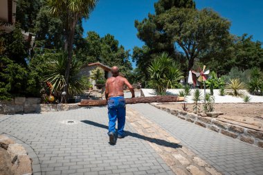 Construction worker carrying two pine boards on a hot day