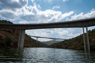 Dağların arasında bulutlu bir günde Portekiz 'de Tua nehri üzerinde iki beton köprü.