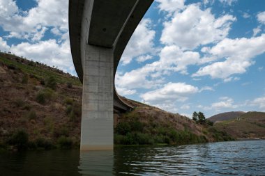 Dağlar arasında bir sütun ve beton bir köprünün güvertesi Portekiz 'de Tua nehrinin üzerinde bulutlu bir günde