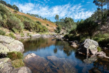 Portekiz 'in Serra do Alvao kentindeki Fisgas de Ermelo kayalıklarından aşağıya doğru giden su yolu boyunca uzanır. Bir günde gökyüzünde bulutlar olur.
