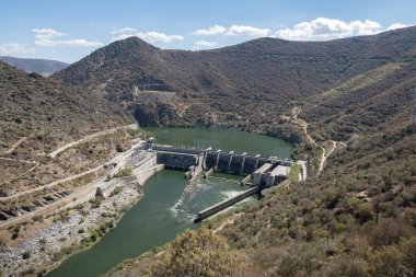 Tepeler ve dağlar arasında Douro nehri ve arka planda Portekiz 'in Tras os Montes kentindeki Valeira hidroelektrik barajı.