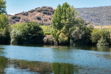 Akıntıya karşı kürek çeken turist, Portekiz 'deki tepeler ve dağlarla çevrili nehir.
