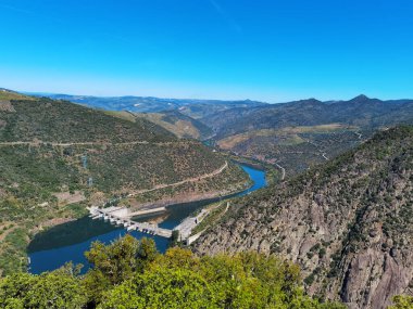 Tepeler ve dağlar arasında Douro nehri ve arka planda Portekiz 'in Tras os Montes kentindeki Valeira hidroelektrik barajı.