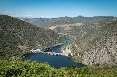 Tepeler ve dağlar arasında Douro nehri ve arka planda Portekiz 'in Tras os Montes kentindeki Valeira hidroelektrik barajı.