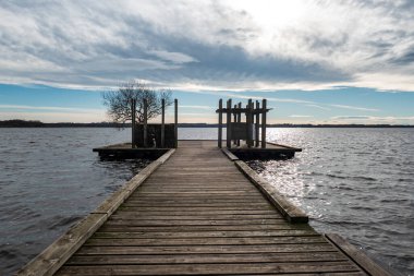 Bulutlu bir kış gününde gölün üzerindeki ahşap iskele.