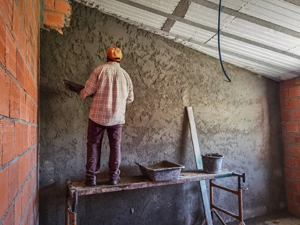 Mason worker putting cement on the wall to finish the wall with plaster