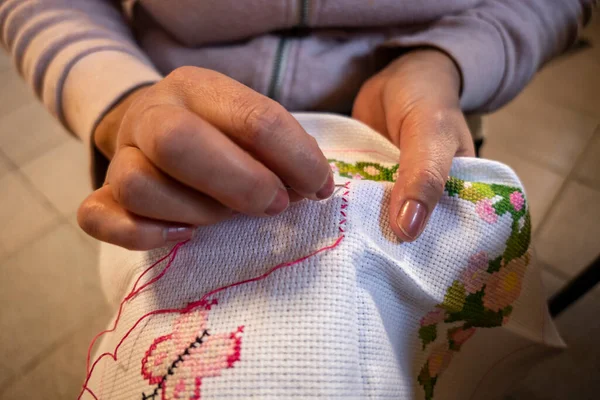 Woman embroidering a cloth making different stitches with colored cotton threads