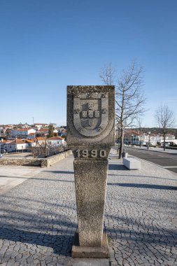 Stone monument with the coat of arms of the Portuguese flag with the description 
