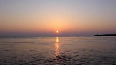 Güneşin ufukta battığı ve güneşin hızla denize yansıdığı bir video.