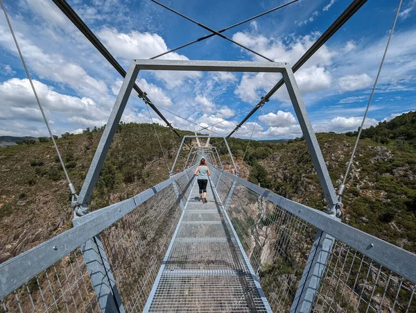Metallic structure of the suspension bridge over the Paiva River with some tourists in the background in Arouca, Portugal
