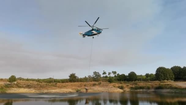 Видео Пожарного Вертолета Заправляющего Ведро Подвешенное Озере Борьбы Лесным Пожаром — стоковое видео