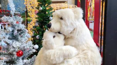 Sıcak bir kucaklaşmada iki oyuncak ayı ve Noel mevsimini temsil eden çeşitli süslemeleri olan birkaç Noel ağacı olan bir video.