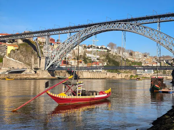 stock image Rabelo boat over the Douro river in Ribeira in Vila Nova de Gaia, with the historic metal bridge Dom Luis I and part of the old city in the background