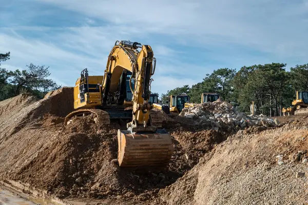 Rotary backhoe excavating earth for the construction of a road