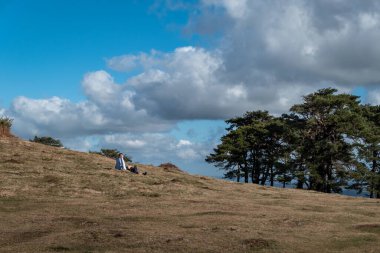 Huzurlu bir keşif: Dağda dinlenen genç turist parçalı bulutlu bir yaz gününde manzaraya hayran.
