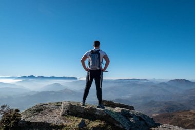 La Rhune 'nin zirvesini keşfeden genç turist büyüleyici panoramik manzaraya hayran kaldı.