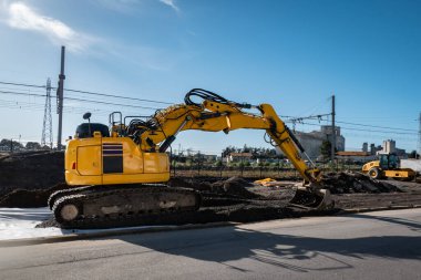 Yağmur suyu drenajına hazırlanmak için zemini düzleştirmeye çalışan kepçe yükleyici