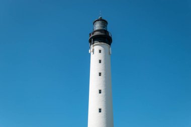 Majestic silhouette: A lighthouse tower rising under a blue sky clipart