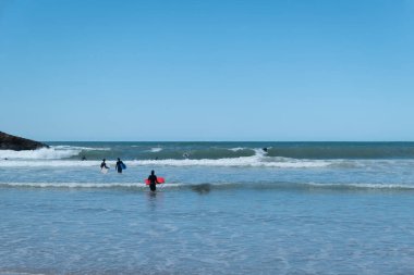Bazı sörfçüler güneşli bir günde dalgaların tadını çıkarırlar.