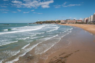 Güneşli bir günde, Biarritz 'de küçük dalgalar, banyo ve sörfçülerle dolu bir sahil.