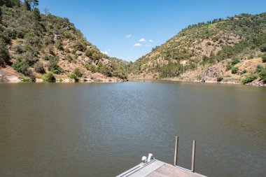 Portekiz 'in Tras os Montes şehrinin arka planında ormanla kaplı dağlarla birlikte Tua nehrinin iskelesinin bir kısmı.