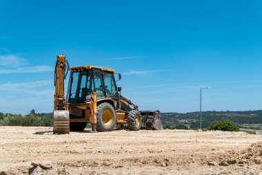 Arazi inşaatı için toprağı dengelemek için kepçe yükleyici çalışıyor