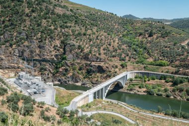 Tepeler ve dağlar arasında Tua nehri üzerinde bir köprü ve Portekiz, Tras os Montes 'te bir elektrik santralinin yanında
