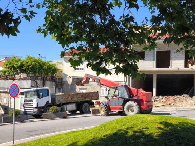 Teleskopik denetim kamyonu caddenin yanındaki konut inşaatından arta kalan artıklarla yüklüyor.