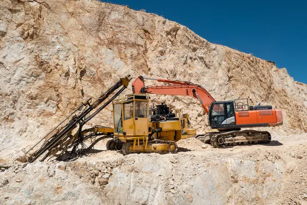 stock image Drilling machine and backhoe in operation: Drilling and excavating soil for quartz extraction