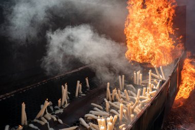 Açık havada yanan mumlar bazıları büyük alevler içinde ve havada büyük bir duman bırakıyor ve diğerleri çoktan sönmüş ve erimiş.
