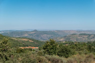 Önünde küçük bir köy, arkasında Portekiz 'in dağları olan yeşil bir manzara.