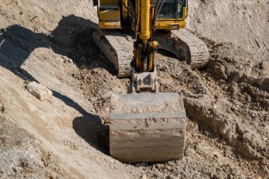 Sürüngen kazıcı kolu iş başında. Yeni yol inşaatı için ön kovayla toprak kazıyor.