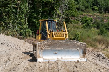 Yol yapımı için toprağı dümdüz eden ön bıçaklı buldozer.