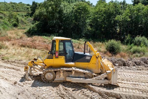 Bulldozer moving earth to build a road in the middle of nature